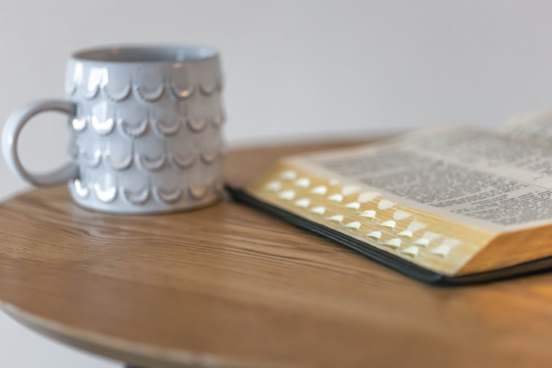 Un libro abierto y una taza sobre una mesa de madera