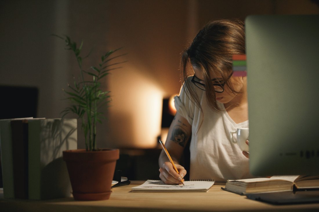 Una persona estudiando en casa con ordenador y cuaderno
